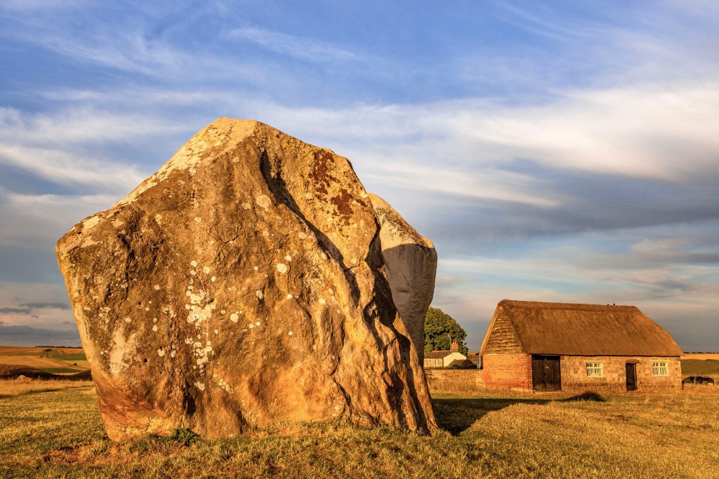 large human placed several ton rock dwarfs house in the Avebury village at Avebury Stone Circle in the UK