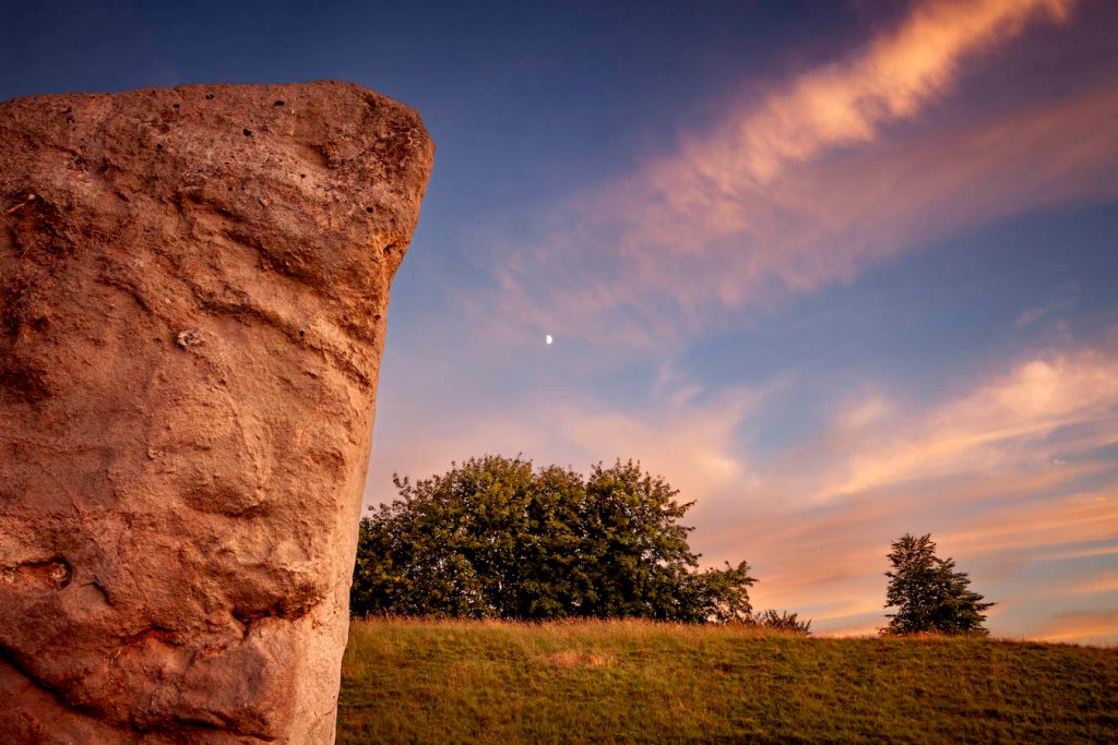 Half moon rise next to ancient stone at Avebury Stone Circle in Avebury, UK