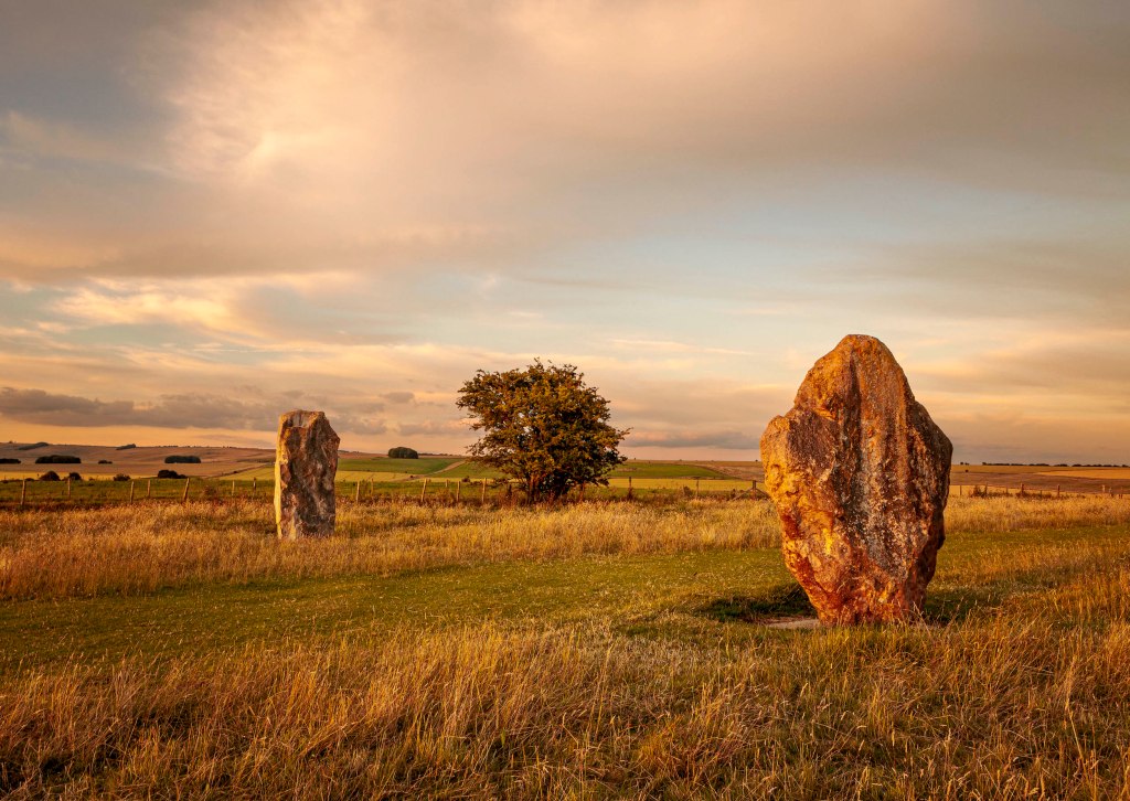 two several ton human placed stones balance and ground each other with the distant tree at Avebury UK