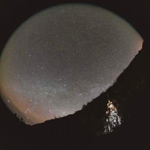 The illuminated frozen waterall in Southern Iceland points to the fisheye capture of the star filled night sky