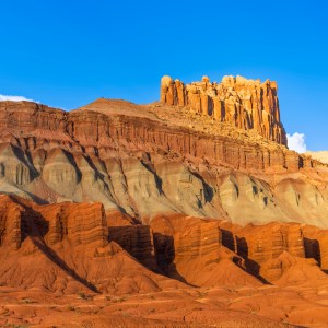 The southwest desert colors of orange, yellow and red, stand out against the utterly blue sky and a few puffy clouds in Capitol Reef National Park.