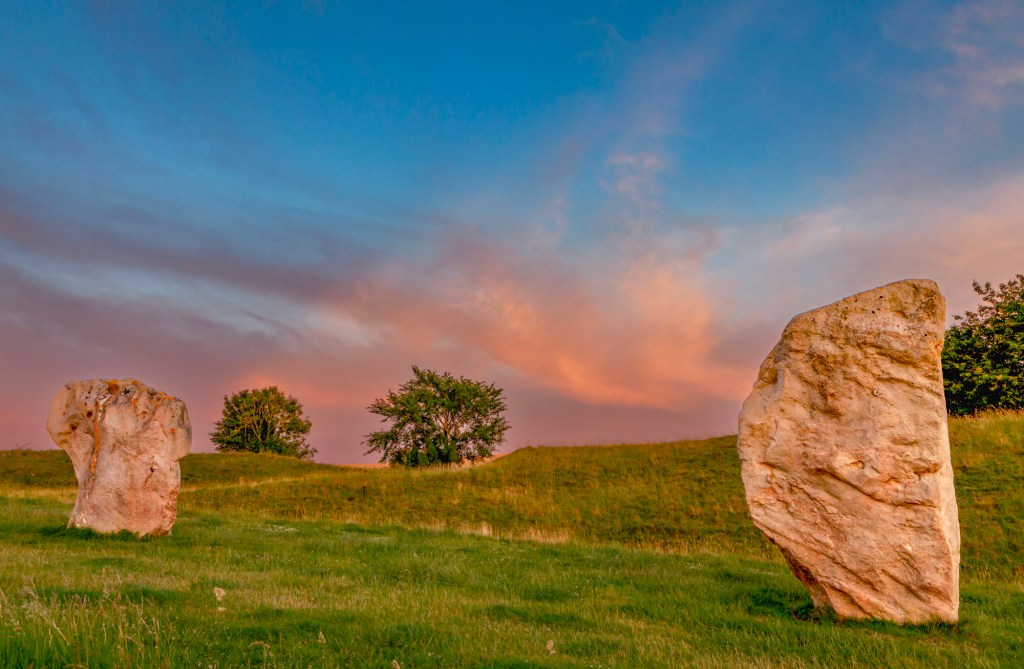 At Avebury Stone Circle in the UK, the last light of orange, pink and yellow graces two of the sacred stones at sunset.