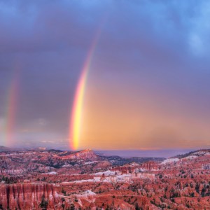 brilliant double rainbow during a sunset storm at Bryce canyon with the setting sun hitting the large rainbow casting an orange glow out from the rainbow like it's on fire