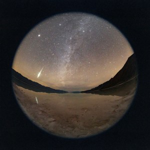 Fireball caught on camera with a fisheye lens reflecting in the temporary lake in Bad Water Basin Death Valley during the Geminid Meteor Shower
